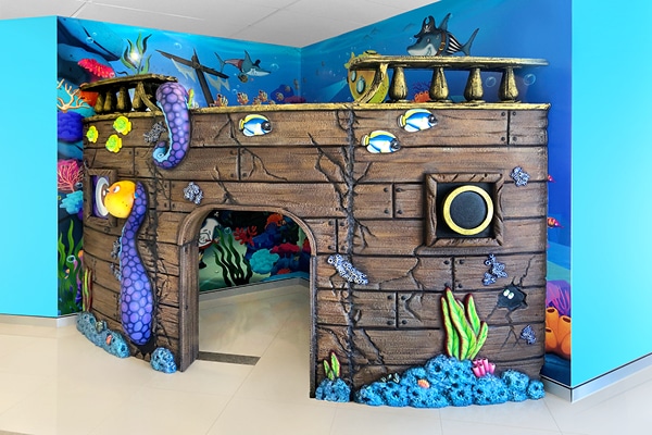 Pirate ship kids fort with a custom planked dividing wall accompanied by an underwater themed mural on interior walls