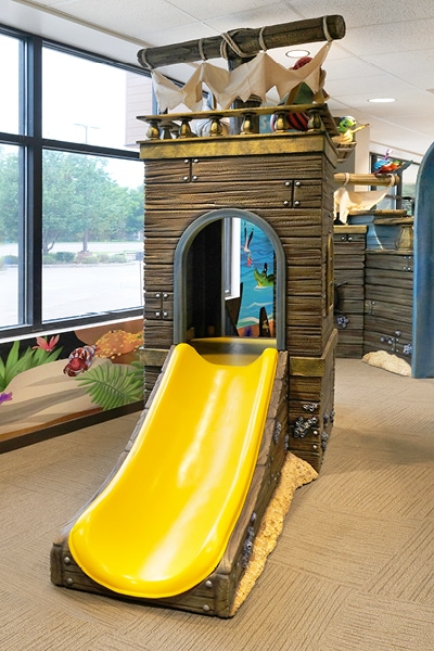 Yellow slide on a pirate ship themed play structure