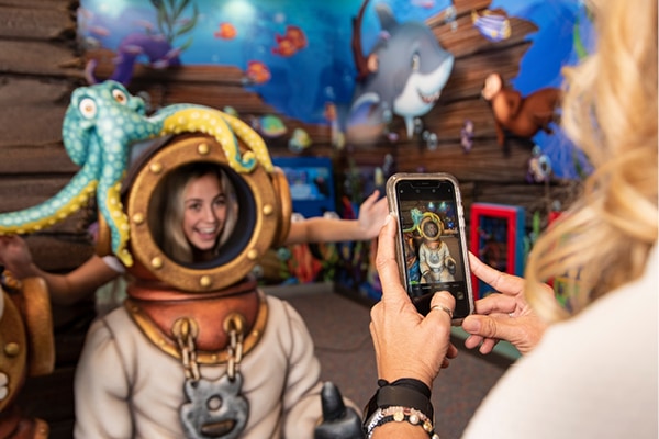 Mother taking a photo of daughter in a divers suit themed photo opportunity.