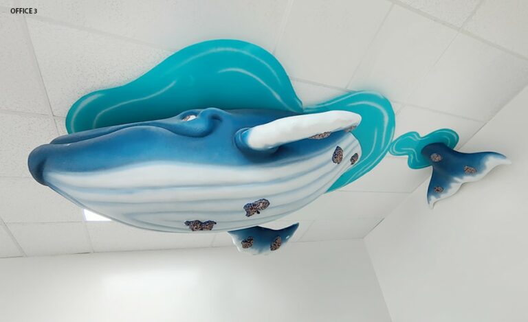 Large blue whale hung from ceiling design to look like it's diving under water from the surface.