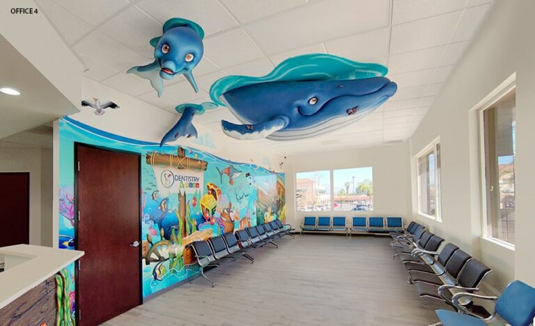Waiting room decorated with giant blue whale and smaller dolphin hung from the ceiling to look like they are diving underwater from the surface.